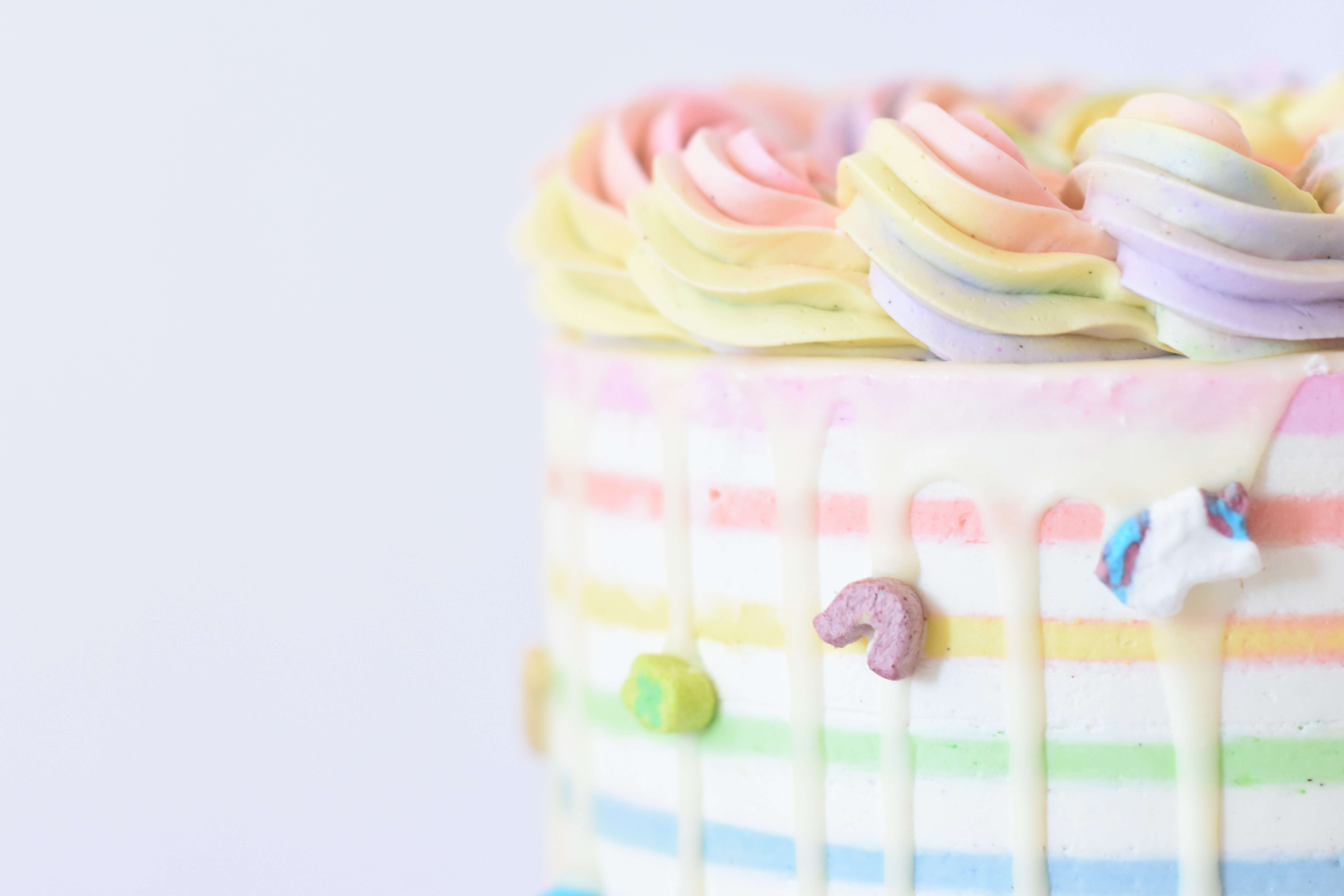 Pastel rainbow buttercream drip cake with rosette piping and marshmallow candy accents, made by Ana Bakes GC