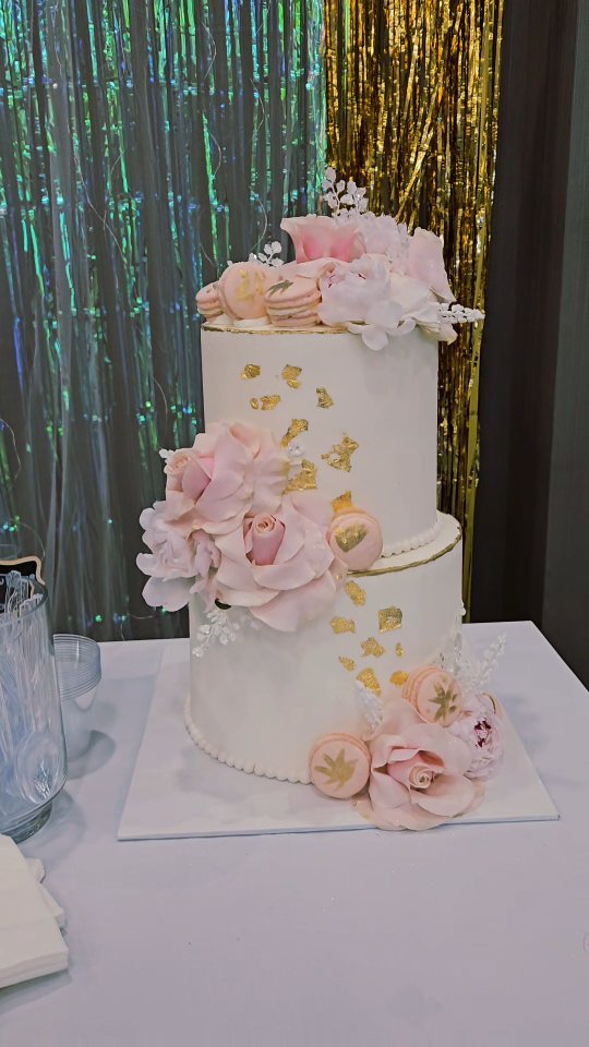 Pink and gold tiered wedding cake with fresh floral accents